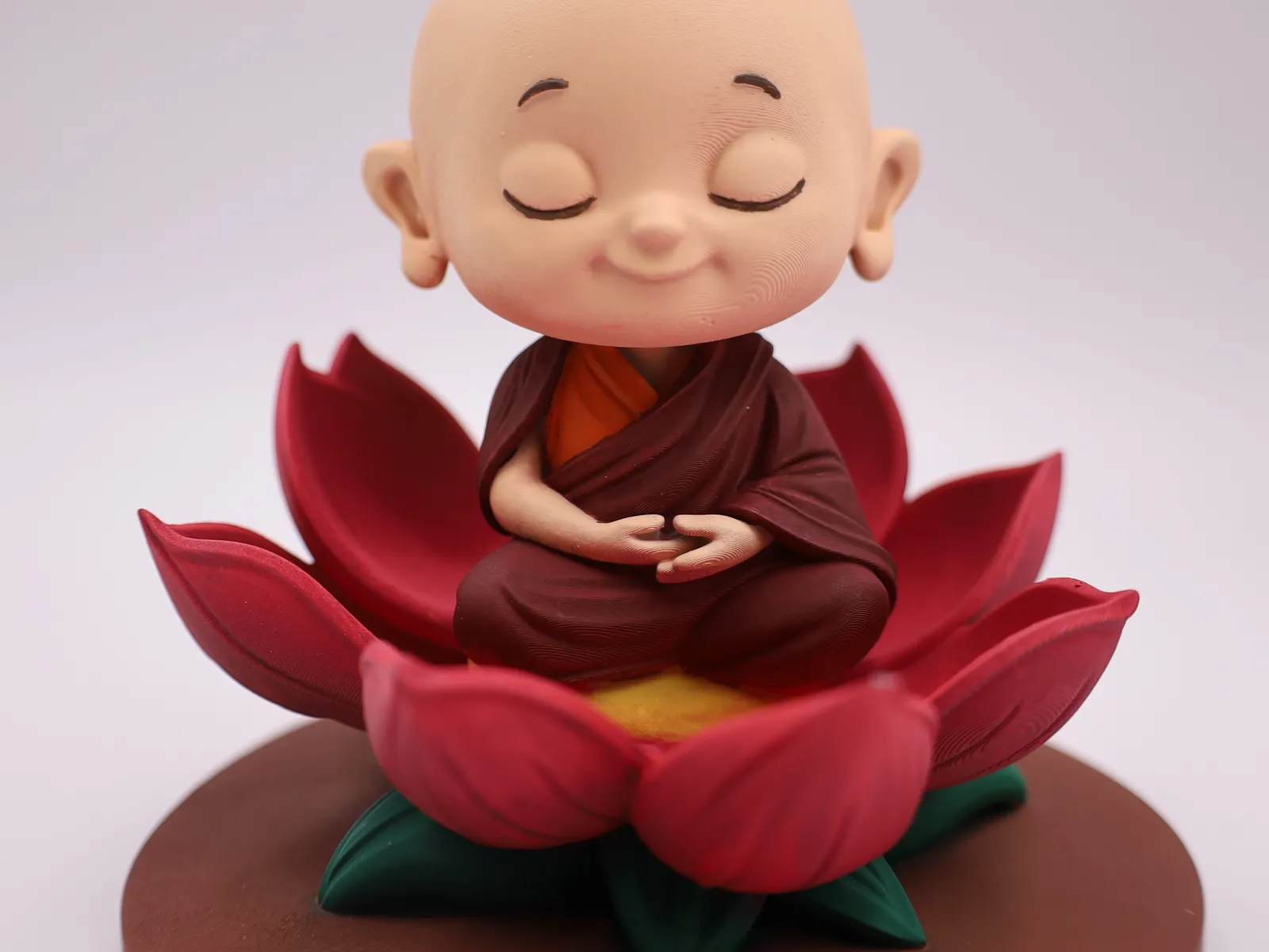 Hand-painted Mini Me monk figurine on a red lotus base
