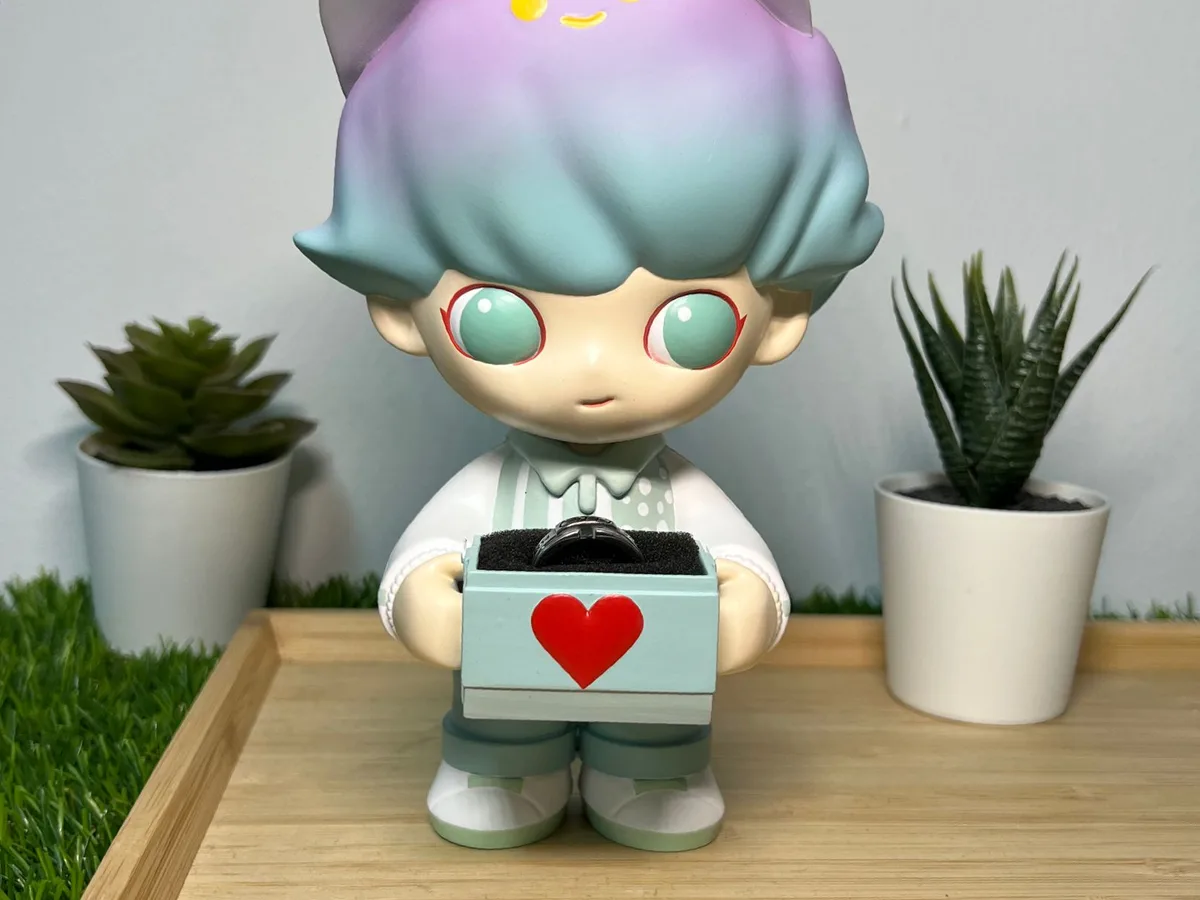 Pastel character figurine holding an engagement ring box